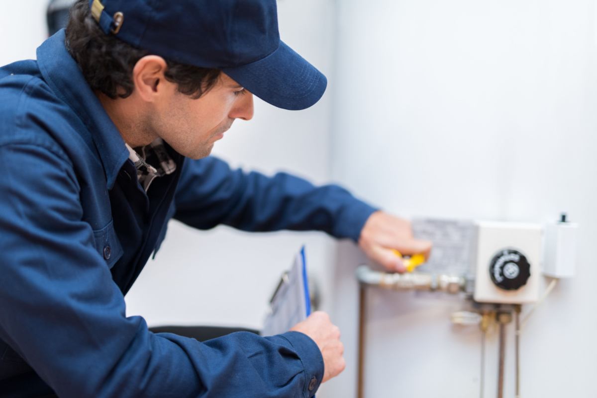 Repair technician fixing a broken water heater tank